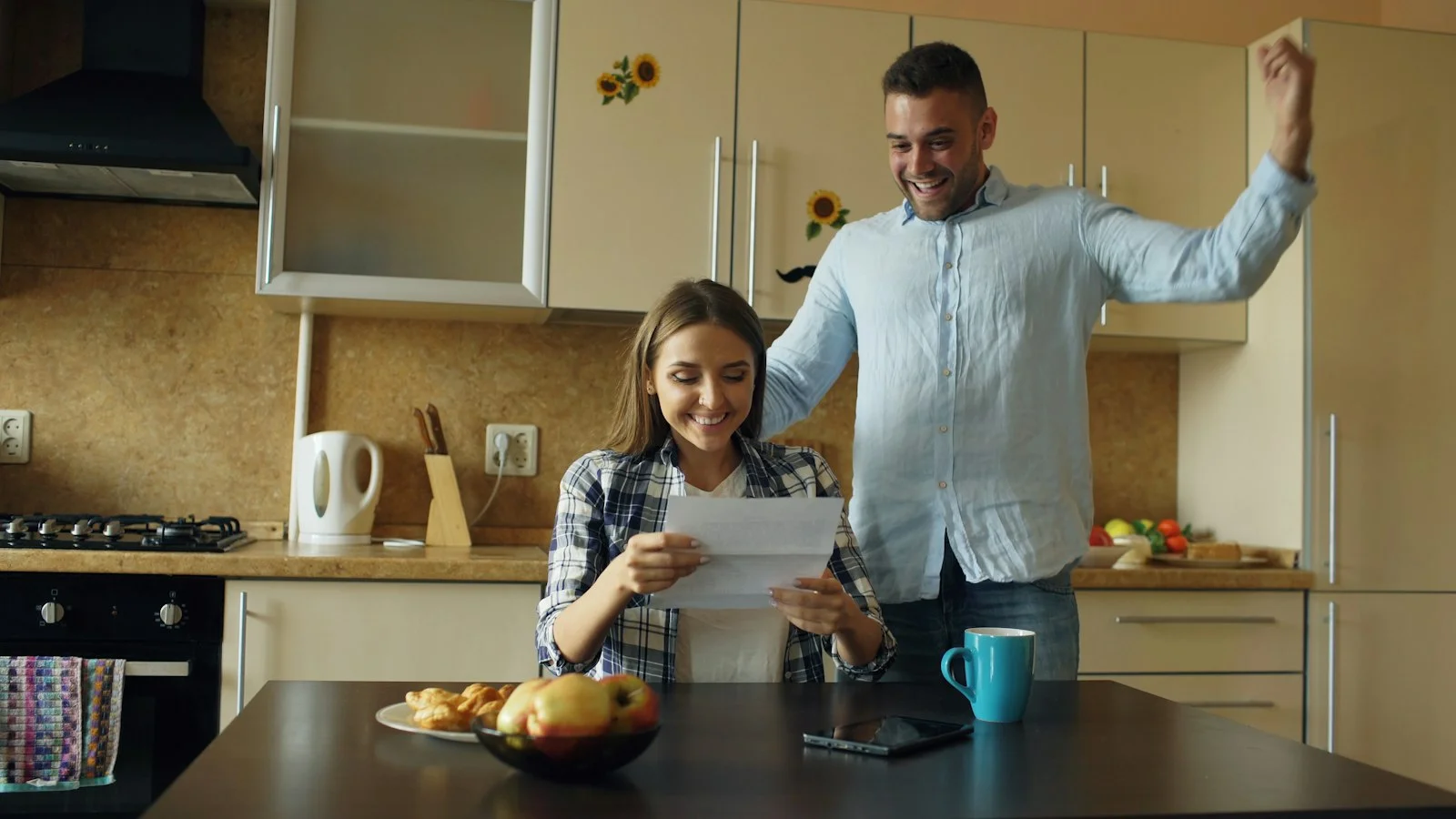 Couple celebrating good news in the kitchen Couple celebrating good news in the kitchen