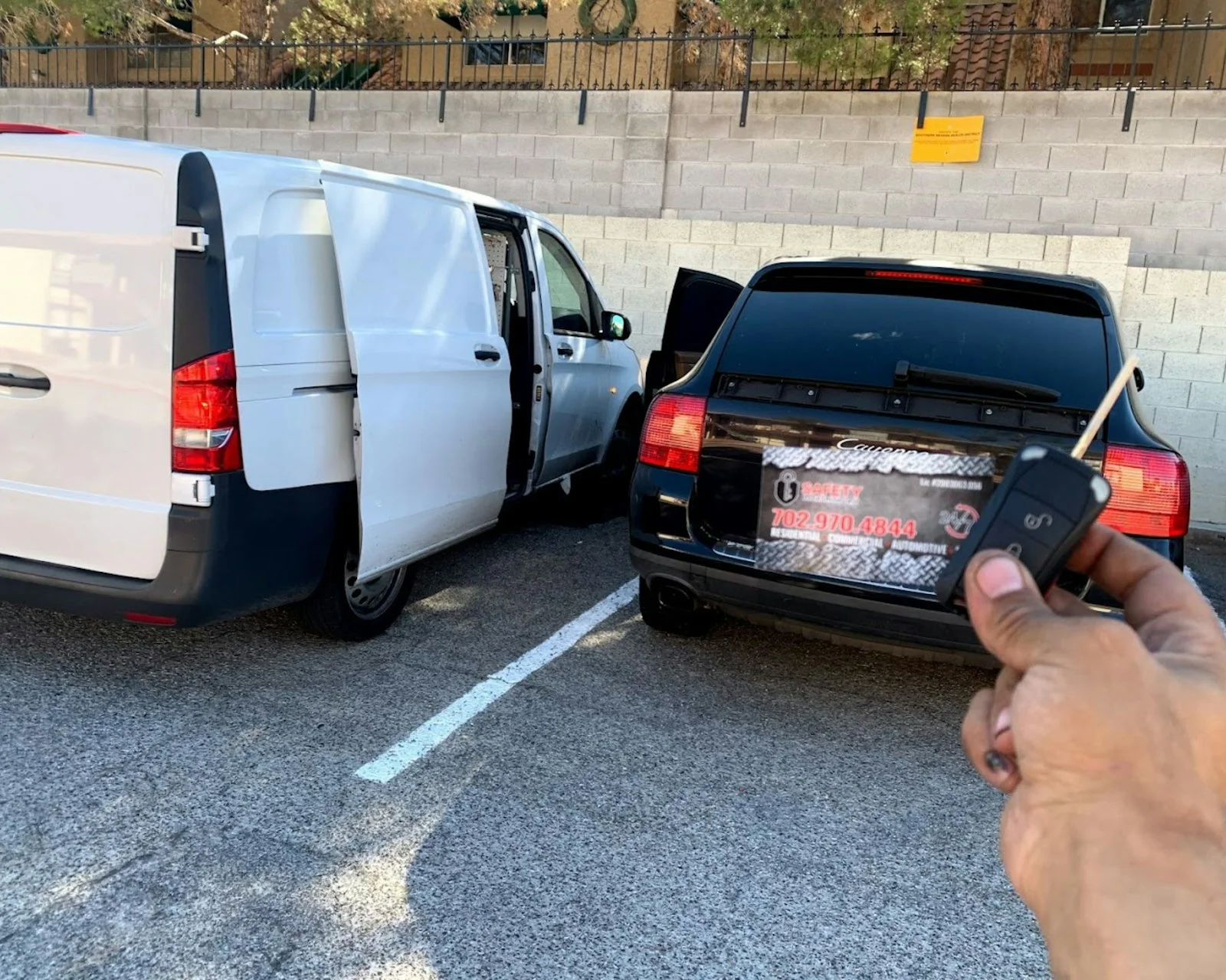 a person holding a remote control next to a van a person holding a remote control next to a van