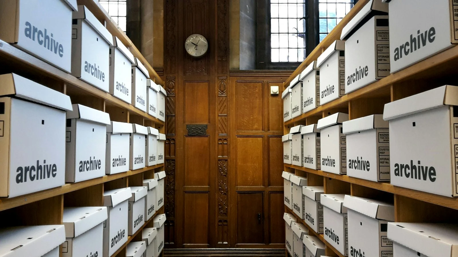 Rows of white archive boxes on wooden shelves Rows of white archive boxes on wooden shelves